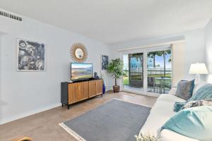 Gone Coastal l Ground Floor Condo l Steps to Beach في Anastasia Island: غرفة معيشة مع أريكة وتلفزيون +30 صورة
