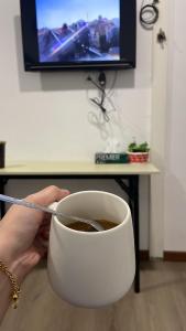 a person holding a cup of coffee in front of a tv at Hillside Suites Kundasang in Ranau +7 photos