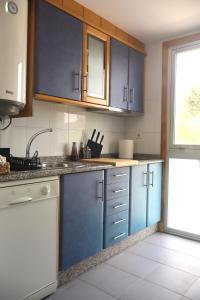a kitchen with blue cabinets and a sink and a window at Casa do Balneario in Arnoia