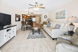 a living room with a couch and a tv at Walk to Beach, Pool & Flagler! Relaxed Condo with Balcony & Full Kitchen in Chicken Island