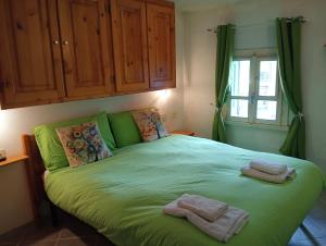 a bedroom with a green bed with two towels on it at canton 520 appartamenti self check in in Livigno