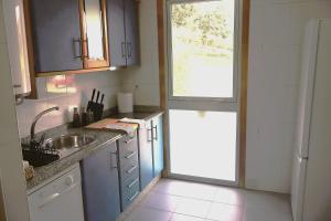 a kitchen with blue cabinets and a sink and a window at Casa do Balneario in Arnoia