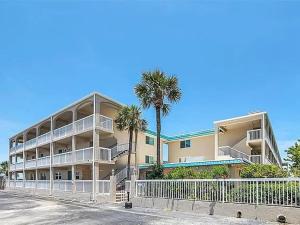 a large building with palm trees in front of it at Walk to Beach, Pool & Flagler! Relaxed Condo with Balcony & Full Kitchen in Chicken Island