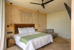 a bedroom with a large bed and a chair at Lalola DownTown Boutique Apartments in Puerto Morelos