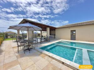 a swimming pool with a table and chairs and an umbrella at Clube Mirante do Iguape in Aquiraz