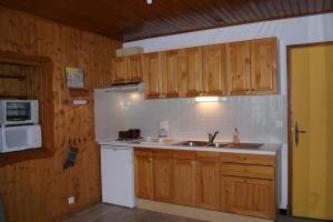 a kitchen with wooden cabinets and a sink and a microwave at Appartement La Petite Cascade in Allos