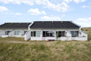 a white house with a black roof in a field at JB358-Brovst-Strandvejen-150-Lejl-126 in Tranum Strand