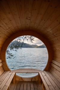 a roundorthole window in a wooden cabin overlooking the water at Wallerei Walchensee in Walchensee +84 photos