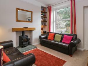 ein Wohnzimmer mit einem Ledersofa und einem Kamin in der Unterkunft Cloud Cottage in Ambleside