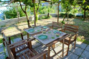 a wooden table with two chairs and a table with plates at Montammare Casa Di Charme in Tramonti +18 photos