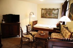 Hotel Koruna Prachatice في براكتايس: غرفة معيشة مع سرير وطاولة وكراسي