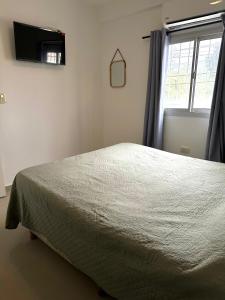 a bedroom with a bed and a window with a television at El Lapacho in Santiago del Estero