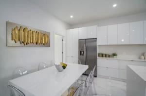 cocina blanca con encimera y nevera en New Construction Villa 2 min Walk to Beach Jacuzzi, en Pompano Beach