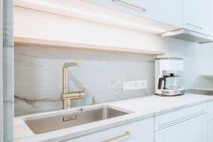 een witte keuken met een spoelbak en een magnetron bij Crystls Aparthotel in Flachau +72 foto's