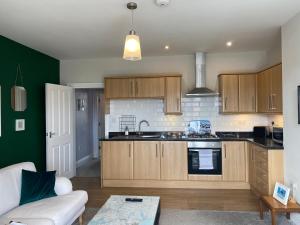 a kitchen with wooden cabinets and a living room at Riverview Apartment with Private Parking in Whitby