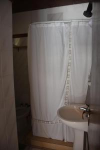 a bathroom with a white shower curtain and a sink at Hostería El Bosque in Villa Gesell