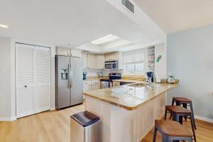 セント・ピート・ビーチにあるArie Dam 301のステンレス製の冷蔵庫と木製の床を備えたキッチン