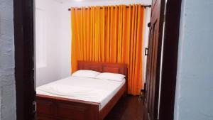 Wanniyankulama West)にあるHelana Holiday Homeのオレンジ色のカーテンが備わる客室の小さなベッド1台分です。 +14枚の写真