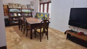 Wanniyankulama West)にあるHelana Holiday Homeのテーブルと椅子とテレビのあるダイニングルーム