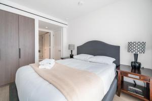 a bedroom with a large white bed and a night stand at Urban Retreat 2BR Condo with Stunning City View in Vancouver +4 photos