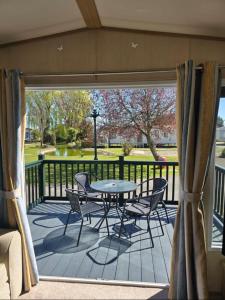 a patio with a table and chairs on a deck at 8 birth Diamond rated Caravan, en-suite, with decking at Parkdean resorts, Southview holiday park in Winthorpe