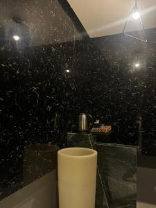 a bathroom with a black wall with a pot on a counter at غرفة وصالة بالدرعية in Riyadh +24 photos