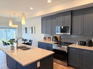 a kitchen with blue cabinets and a stove top oven at Family Friendly Spaciousking Bed Wifisleeps 12 in Edmonton