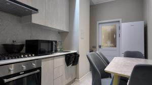 a kitchen with a stove and a table with chairs at Tashkent City Gardens Residence E7-4-25 in Tashkent