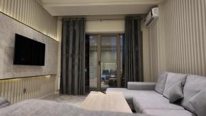 a living room with a couch and a tv at Tashkent City Gardens Residence E7-4-25 in Tashkent