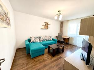 a living room with a blue couch and a desk at Berzei Astra - Rise Apartments in Braşov +7 photos