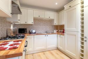 une cuisine avec des armoires blanches et un four à plaques de cuisson dans l'établissement Cuthbert Cottage, à Beadnell