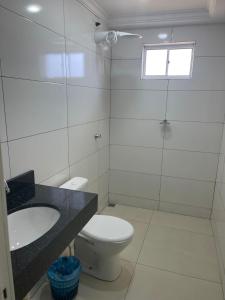 a bathroom with a toilet and a sink and a window at Vitalliti Hotel in Alta Floresta