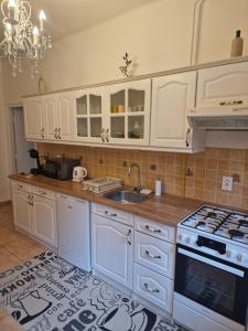 a kitchen with white cabinets and a sink at Patak apartman in Eger +4 photos