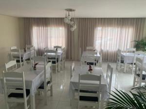 a dining room with white tables and white chairs at Vitalliti Hotel in Alta Floresta