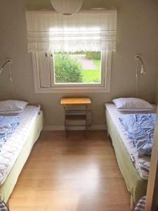two beds in a room with a window and a table at VGO715-Hova-Hulan-Strandvaegen-9 in Vallsjöbol
