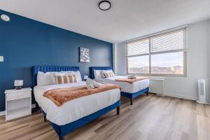 a blue bedroom with two beds and a window at Upscale 2BR Condo with Gym and Free Parking in Arlington
