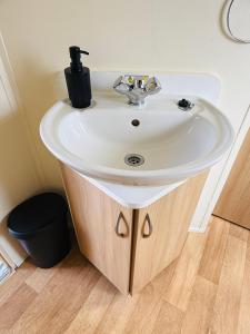 Un lavabo blanco en un baño junto a un suelo de madera. en 'Olive' by the Sea, en Whitley Bay 36 fotos más