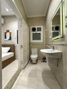 ein Badezimmer mit Waschbecken und Toilette und ein Bett in der Unterkunft October Square in Madinat as-Sadis min Uktubar