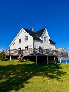 a large white house with a deck on the grass at Cozy familyhouse with free parking & fantastic view in Tromsø