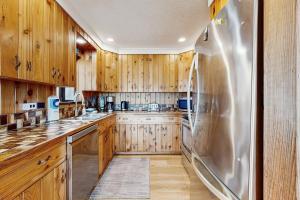 a kitchen with wooden cabinets and a stainless steel refrigerator at A Wave From It All in Rockaway Beach +15 photos