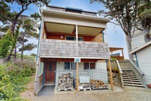a house with a porch with a lot of wood at A Wave From It All in Rockaway Beach