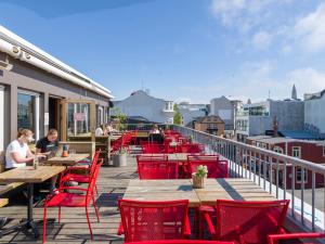 a deck with red chairs and tables on a building at Loft - HI Eco Hostel in Reykjavík