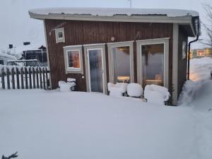 a cabin covered in snow in front of a fence at Modern cottage, quiet area with good bus connection in Luleå