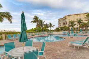 a pool with chairs and a table with a umbrella at Ocean View Top-Floor Sunset Vistas Condo! in St Pete Beach
