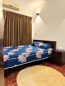 a bedroom with a bed with a blue blanket with flowers at Premium 3 BR Apartment in Uttara Near Airport and Metro Sector 7 AC Wifi Modern Comfort in Bāiljuri