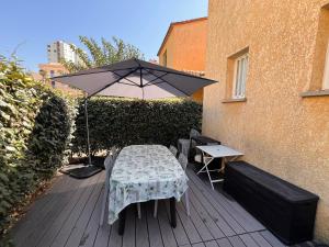 un patio avec une table et un parasol dans l'établissement Maison Familiale dans le Domaine de la Plage avec Piscine Privée, à 200m de la Mer, à Valras-Plage