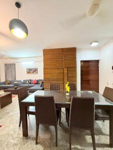 a living room with a table and chairs and a couch at Premium 3 BR Apartment in Uttara Near Airport and Metro Sector 7 AC Wifi Modern Comfort in Bāiljuri