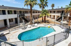 a pool in front of a building with palm trees at Renovated Downtown Phoenix Condo in Phoenix