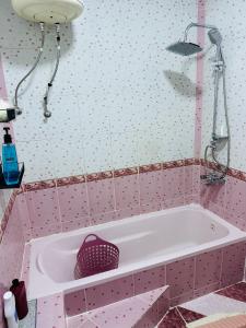a pink bathroom with a tub and a shower at شقة مفروشة واسعة وهادئة in Umm Juraysāt +24 photos