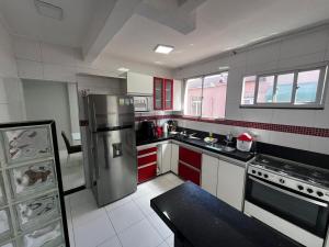a kitchen with red cabinets and a stainless steel refrigerator at Itapuã - 4 Minutos da Praia - Apartamento Espaçoso - 3 Quartos in Vila Velha